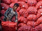 A worker unloads sacks of onions from a truck, at a wholesale vegetable market in Jalandhar