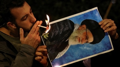 A demonstrator lights a cigarette with fire from a burning picture of Iran's Supreme Leader Ayatollah Ali Khamenei outside the Iranian embassy during a rally in support of nationwide protests in Iran, in London, Britain, January 12, 2026 (REUTERS)