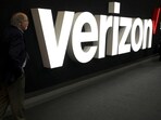 A man stands next to the logo of Verizon at the Mobile World Congress in Barcelona, Spain