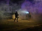 Law enforcement officers stand amid tear gas at the scene of a reported shooting Wednesday