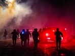 Federal agents stand guard after deploying tear gas as community members protest 