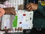 Election Commission of India (ECI) staff break the seal of an Electronic Voting Machine (EVM) as polling agents of various political parties look on before starting tabulation of votes at a counting centre for the Maharashtra state assembly elections in Mumbai. (Photo by Indranil Mukherjee / AFP)
