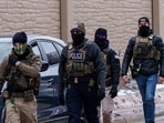 Immigration and Customs Enforcement (ICE) agents, including one wearing a 'NOT ICE' face covering, walk near their vehicles, in Richfield, Minnesota.