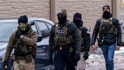 Immigration and Customs Enforcement (ICE) agents, including one wearing a 'NOT ICE' face covering, walk near their vehicles, in Richfield, Minnesota. (AP) Immigration and Customs Enforcement (ICE) agents, including one wearing a 'NOT ICE' face covering, walk near their vehicles, in Richfield, Minnesota. (AP)