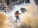 A protesting community member attempts to protect themselves as federal agents fire munitions and pepper balls, amid protests in Minneapolis.