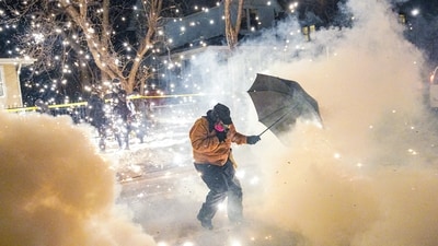 A protesting community member attempts to protect themselves as federal agents fire munitions and pepper balls, amid protests in Minneapolis. (REUTERS)