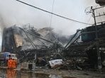 Firefighters gather beside a collapsed portion of a multi-story shopping mall following a massive fire that broke out overnight, in Karachi, Pakistan.