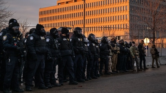 Federal law enforcement officers watch as demonstrators against the Immigration and Customs Enforcement (ICE) deployment protest outside the Bishop Henry Whipple Federal Building in St. Paul, Minnesota, US, on Saturday, Jan. 17, 2026. (Photographer: Victor J. Blue/Bloomberg)(Bloomberg)