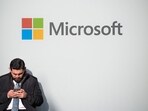 A man uses a phone next to a Microsoft logo during the 56th annual World Economic Forum meeting, in Davos, Switzerland, on 20 January 2026.