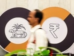 A man walks past a logo of the Reserve Bank of India and the Indian Rupee inside the RBI headquarters in Mumbai. By selling US Treasury holdings, RBI can then use the funding to purchase rupees to strengthen its value.