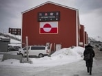 A woman walks in front of a building displaying the Greenlandic flag in Nuuk, Greenland.
