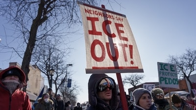 A demonstrators carries a sign that reads ‘Neighbors say ICE OUT’ near the site where a 37-year-old protester was fatally shot by federal agents amid a scuffle to arrest him in Minneapolis. (Tim Evans/REUTERS)