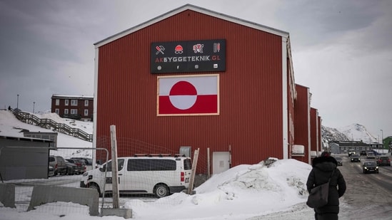 A woman walks in front of a building displaying the Greenlandic flag in Nuuk, Greenland. (AFP)