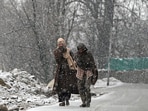 People walk during snowfall on the outskirts of Srinagar. 