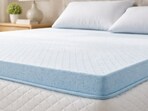 Soft memory foam mattress topper layered on a bed, showing plush texture and added height for comfort and spinal alignment.