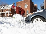 A resident clears snow from around a parked car on a residential street in the aftermath of a winter storm in the St. Louis area, Missouri, US
