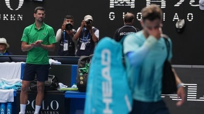 Novak Djokovic, left, of Serbia reacts as Lorenzo Musetti of Italy walks from the court after withdrawing from their quarterfinal match at Australian Open (AP) Novak Djokovic, left, of Serbia reacts as Lorenzo Musetti of Italy walks from the court after withdrawing from their quarterfinal match at Australian Open (AP)