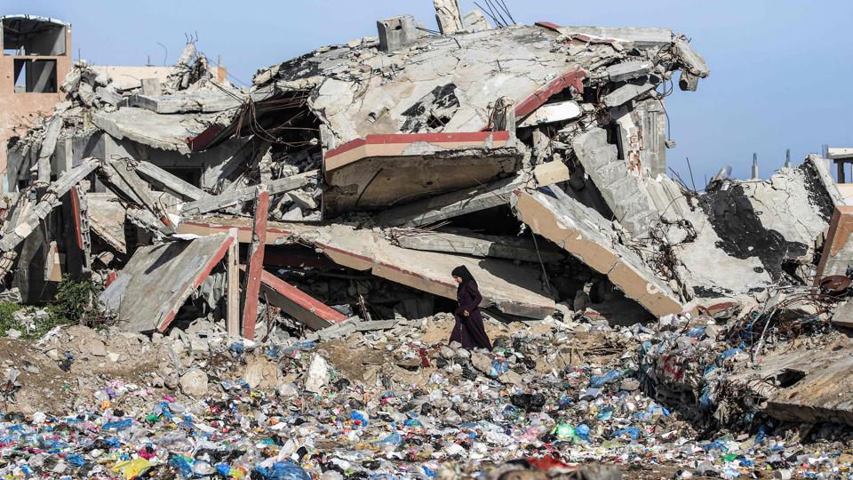 A woman walks past heaps of trash discarded near a destroyed building in the Nuseirat camp for Palestinian refugees north of Deir al-Balah in the central Gaza Strip on January 29 (AFP) A woman walks past heaps of trash discarded near a destroyed building in the Nuseirat camp for Palestinian refugees north of Deir al-Balah in the central Gaza Strip on January 29 (AFP)