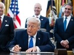 Donald Trump, center, signs an executive order in the Oval Office of the White House