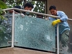 Forensic team members remove a shattered glass pane from the balcony of filmmaker Rohit Shetty. 