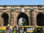 This photograph taken on November 20, 2025 shows commuters riding past the Teen Darwaja, a triple-arched historical gateway, in Ahmedabad. (AFP FILE)