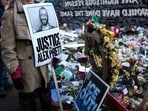 A woman holds a "Justice for Alex Pretti" sign at the makeshift memorial set up near the street where he was shot and killed by federal immigration agents in Minneapolis, Minnesota, on January 31, 2026. (Photo by CHARLY TRIBALLEAU / AFP)