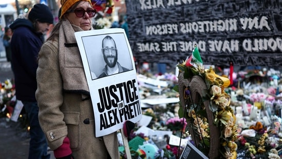 A woman holds a "Justice for Alex Pretti" sign at the makeshift memorial set up near the street where he was shot and killed by federal immigration agents in Minneapolis, Minnesota, on January 31, 2026. (Photo by CHARLY TRIBALLEAU / AFP) (AFP)