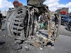 Bystanders walk past a burnt vehicle along a road on the outskirts of Quetta on February 1, 2026 a day after an alleged attack by Baloch militants