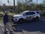 A person walks a dog as members of the Pima County sheriffs office remains outside of Nancy Guthrie's home.