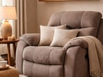 A cosy living room corner featuring a plush recliner, soft lighting, and layered cushions for relaxed evenings at home.(Ai generated)