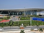Commuters ride past the Kempegowda International Airport in Bengaluru on December 9, 2025.