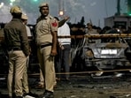 Police personnel stand beside charred vehicles at the blast site after an explosion near the Red Fort in the old quarters of Delhi.