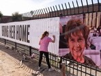 Jennifer Bond signs a banner that reads "Bring her home" and shows a photo of Nancy Guthrie, U.S. television journalist Savannah Guthrie's abducted elderly mother, at the KVOA newsroom, where Savannah worked earlier in her career, in Tucson, Arizona, U.S., February 12, 2026.