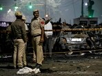 Police personnel stand beside charred vehicles at the blast site after an explosion near the Red Fort in the old quarters of Delhi. Police personnel stand beside charred vehicles at the blast site after an explosion near the Red Fort in the old quarters of Delhi.