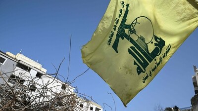 A flag of the Lebanese Shiite movement Hezbollah flutters above the rubble of a building that was hit in January by an Israeli strike in the southern Lebanese village of Qannarit, on February 16, 2026. (AFP)
