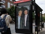 Commuters walk past a bus stop near Nine Elms Station in London as activists put up a poster showing US President Donald Trump and Jeffrey Epstein. 
