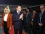 France's President Emmanuel Macron (C) reacts next to his wife Brigitte Macron (L) upon their arrival in Mumbai on February 17, 2026. The French president begins a three-day official visit to Mumbai and then New Delhi, his fourth trip to India since 2018, which will be punctuated by a series of events alongside the Indian Prime Minister. (Photo by Ludovic MARIN / AFP)