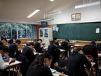 In this picture taken on October 13, 2017, students take an exam as portraits of late North Korean leaders Kim Il Sung and Kim Jong Il are seen in a classroom at Tokyo Korean high school in Tokyo. Portraits of North Korea's late leaders hang proudly in the classrooms of the Korean High School in Tokyo, where the recent surge in tensions over Pyongyang’s nuclear weapons programme have seen faculty and staff subjected to death threats. / AFP PHOTO / Behrouz MEHRI / TO GO WITH AFP STORY JAPAN-NKOREA-SKOREA-SOCIETY-EDUCATION BY HARUMI OZAWA (AFP)