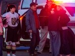 People embrace and walk away as police stand outside the perimeter they created around the Dennis M. Lynch Arena where a shooting occurred earlier today in Pawtucket, Rhode Island, on February 16, 2026. (Photo by Joseph Prezioso / AFP)