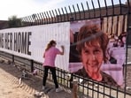 Jennifer Bond signs a banner that reads "Bring her home" and shows a photo of Nancy Guthrie
