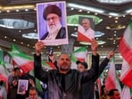 A man holds a picture of Iran's Supreme Leader Ayatollah Ali Khamenei and another of slain Islamic Revolution Guards Corps (IRGC) Commander Qasem Soleimani during an event at the Tehran Musalla.