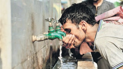 TOPSHOT - An Indian labrourer drinks water at a public water fountain on a hot summer day in the old quarters of New Delhi on May 1, 2018. / AFP PHOTO / Sajjad HUSSAIN (AFP)