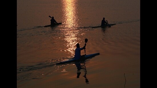 Rowers practising in the glistening waters of Sukhna Lake with the setting sun in the backdrop. (Keshav SIngh/HT)