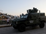 A man walks past Mexican soldiers on patrol in an armored vehicle, after authorities reinforced security following roadblocks and arson attacks carried out by organised crime in several states, in the aftermath of a military operation in which Mexican drug lord Nemesio Oseguera, known as "El Mencho," was killed 