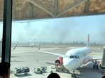 People watch from the Guadalajara International Airport as smoke billows amid a wave of violence