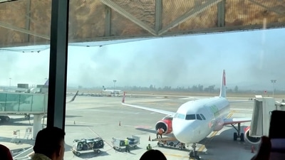 People watch from the Guadalajara International Airport as smoke billows amid a wave of violence (Paco Villanueva via REUTERS)