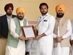 Mann hands over a framed citation to a local representative at the Sardulgarh event in Mansa on February 24, 2026.