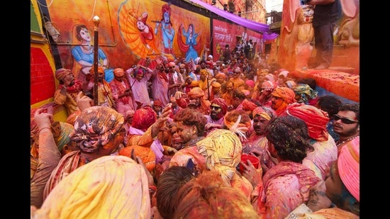 Revellers celebrate Lathmar Holi, the Hindu spring festival of colours, next to a wall mural of Lord Krishna in Barsana on Wednesday (AFP)