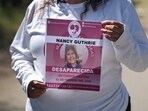 A missing poster for Nancy Guthrie is held as authorities continue to search for the 84-year-old. 