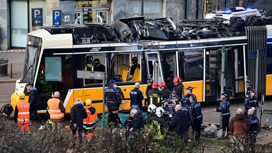 Italian police officers and firefighters operate at the site of a tram derailment in Milan on February 27, 2026. (AFP)